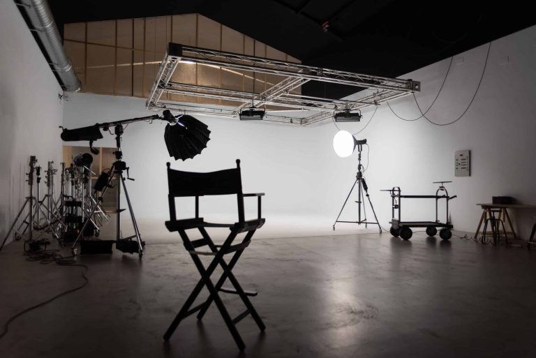 Set de videoclip montado en el ciclorama blanco, con focos, truss y silla de director