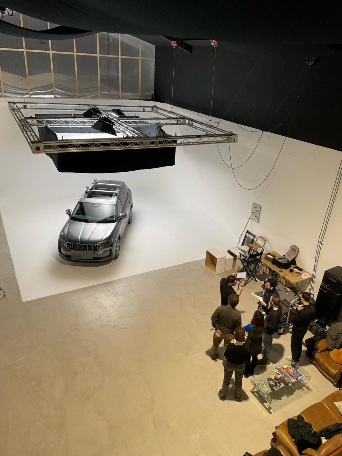 Equipo de rodaje publicitario alrededor de un SUV en el ciclorama blanco