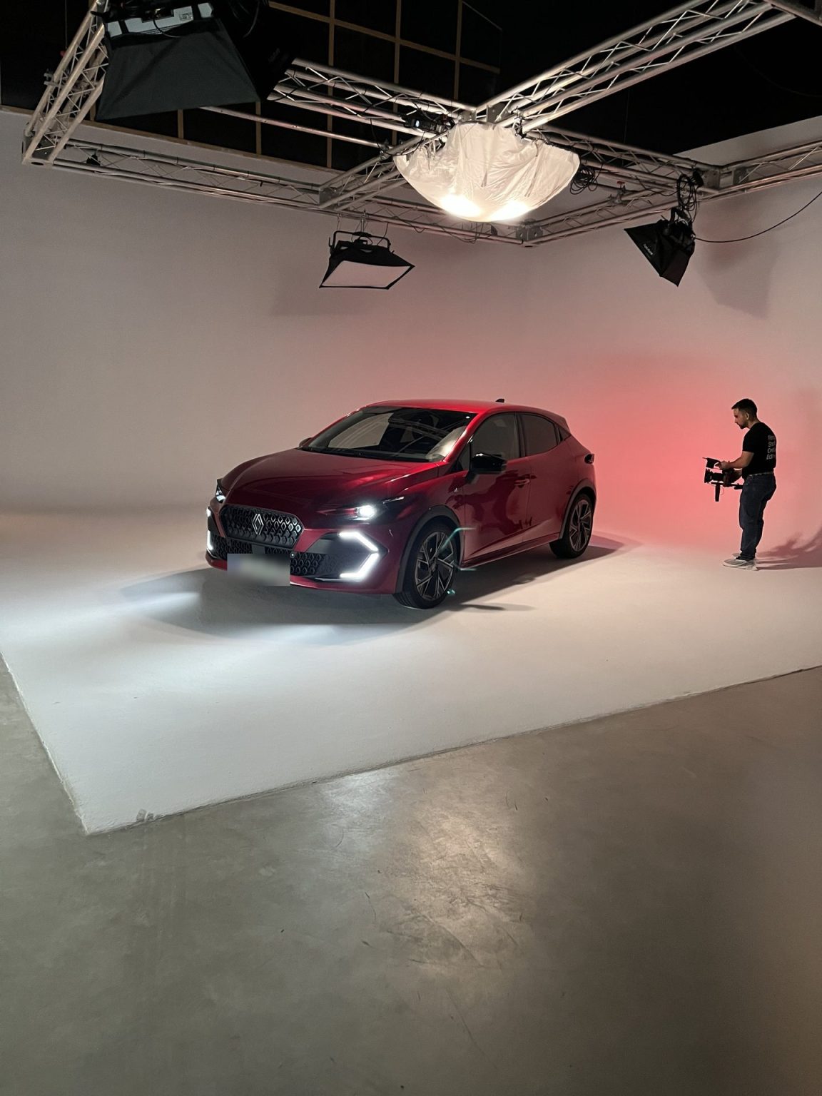Coche sobre tarima blanca con fondo degradado rojo durante el rodaje de un spot