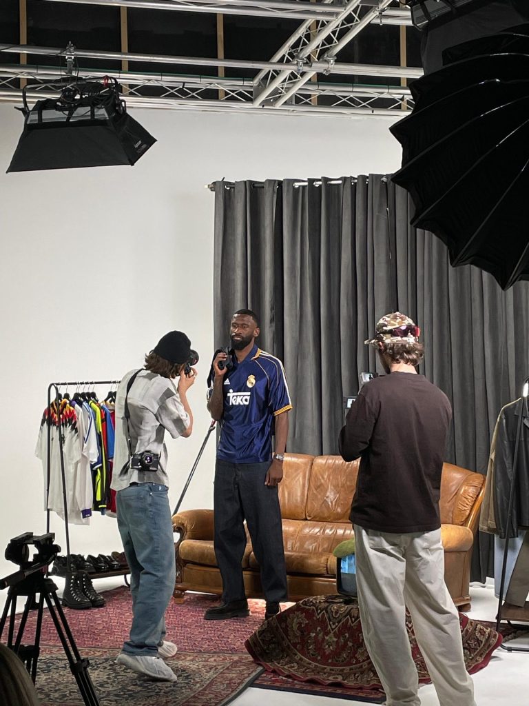 Sesión de fotos de moda en set decorado con sofá de cuero y percheros